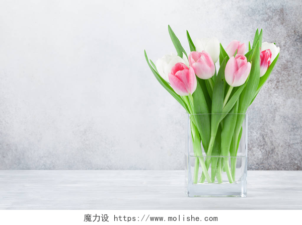 郁金香插在了白色的玻璃瓶里复活节贺卡与郁金香花花束。在石墙前, 有空间为您问好